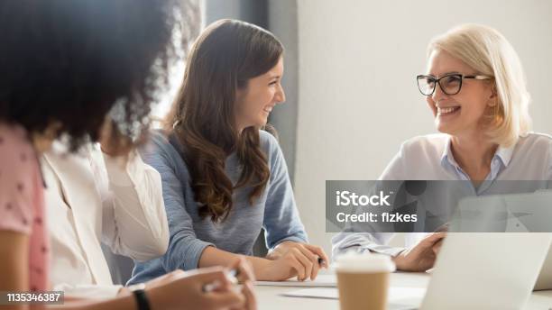 Friendly Smiling Old And Young Businesswomen Talking Laughing At Meeting Stock Photo - Download Image Now