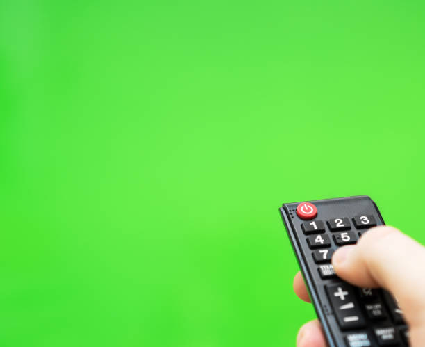 istock Male hand with TV remote control over green screen. Place for your advertisement. 1135346476