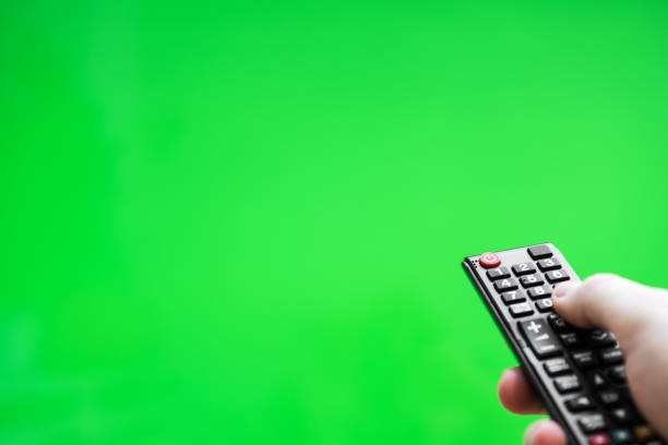 istock Male hand with TV remote control over green screen. Place for your advertisement. 1135346478