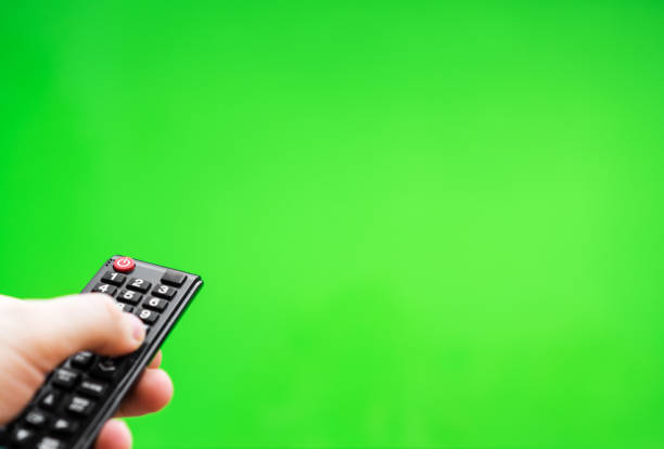 istock Male hand with TV remote control over green screen. Place for your advertisement. 1135346484