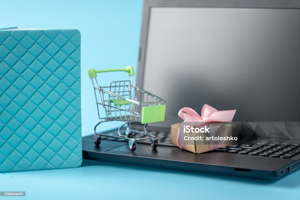 Koszyk i nagroda pudełko na prezent na klawiaturze laptopa na niebieskim tle. Zniżki i zakupy w sklepach internetowych - Zbiór zdjęć royalty-free (Biznes) Koszyk i nagroda pudełko na prezent na klawiaturze laptopa na niebieskim tle. Zniżki i zakupy w sklepach internetowych - Zbiór zdjęć royalty-free (Biznes)
