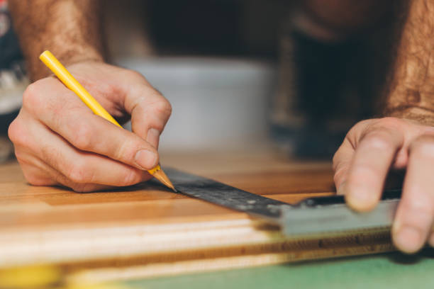 the master prepares the board for the cut-off - repair and finishing work - carpenters pencil imagens e fotografias de stock