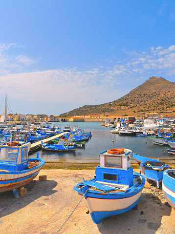 04.09.2018. view of the port of Favignana with small fishing boats, typical houses and sea and mountains in background, Sicily Italy