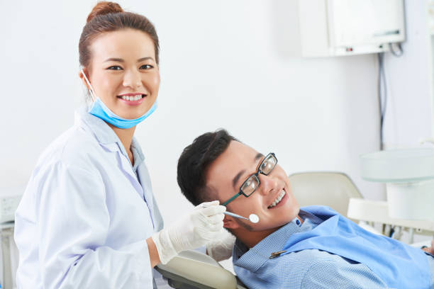 стоматолог изучает зубы молодого человека - dentist asian ethnicity portrait male стоковые фото и изображения