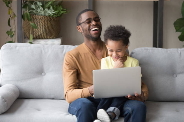 istock African father and cute kid son having fun with computer 1135353568