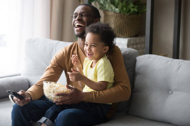 istock Happy african dad and kid son laughing watching funny comedy 1135353570