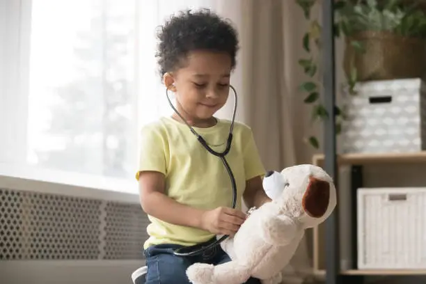 Photo of Cute african boy playing with toy as doctor holding stethoscope