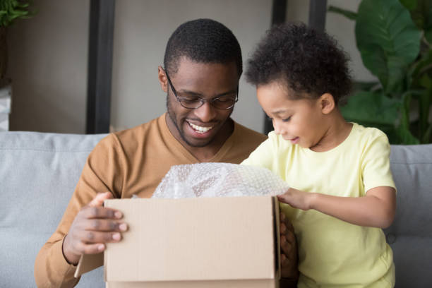 istock Happy black father and little kid son open cardboard box 1135353600