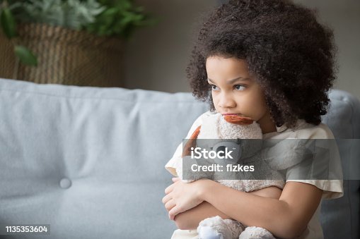 istock Upset lonely african kid girl holding teddy bear looking away 1135353604