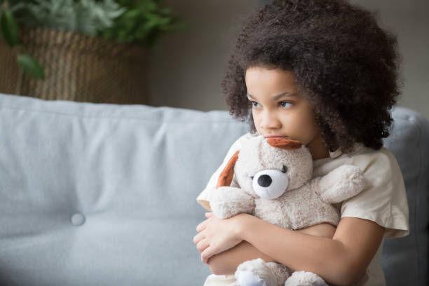 Upset lonely african kid girl holding teddy bear looking away Upset lonely bullied little african american kid girl holding teddy bear looking away feels abandoned abused, sad alone preschool mixed race child orphan hugging stuffed toy, charity adoption concept child sadness stock pictures, royalty-free photos & images