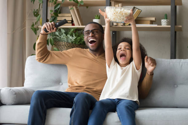 istock Happy overjoyed black father with kid daughter watching tv game 1135353612