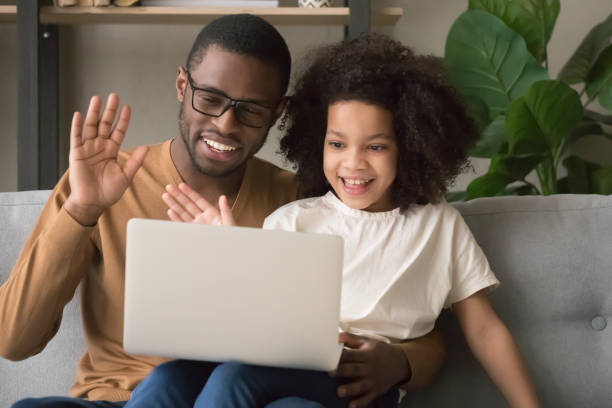 istock Happy black dad with kid daughter waving hands making videocall 1135353618