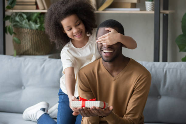 istock African kid daughter closing eyes congratulating dad giving gift box 1135353622