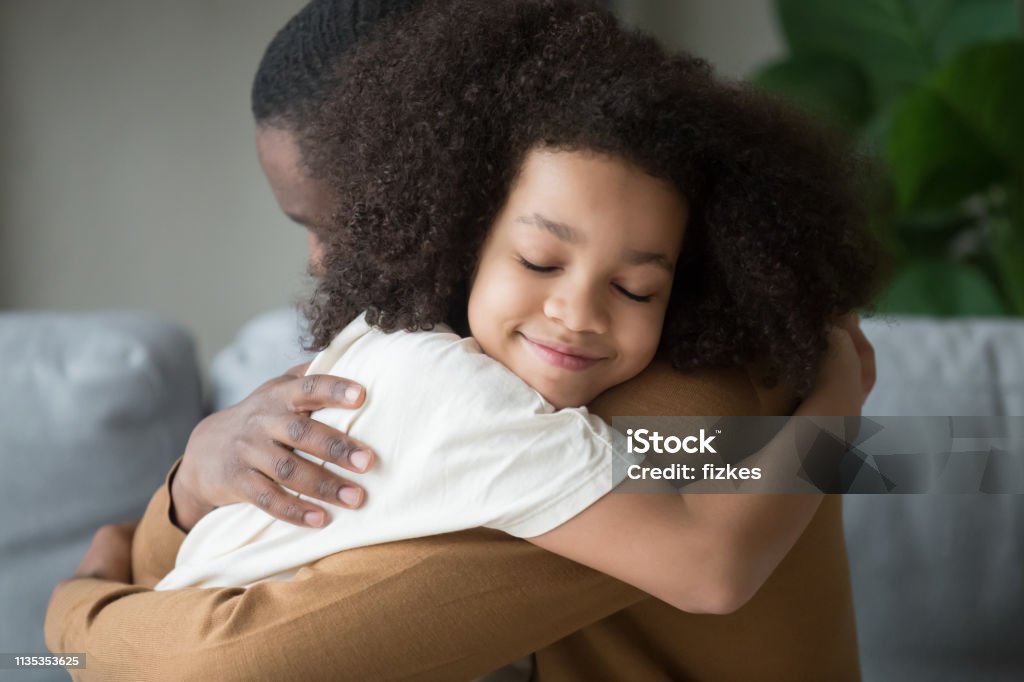Cute mixed race child daughter embracing father feeling love connection Cute funny mixed race child daughter embracing black father holding tight feeling love connection affection concept, happy african family dad and little kid girl hugging cuddling bonding at home Child Stock Photo