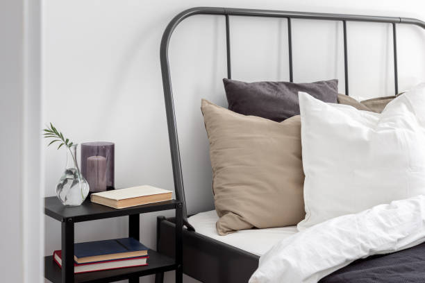 Bed with metal headboard Simple bed with metal headboard and black wooden nightstand bed decoration stock pictures, royalty-free photos & images