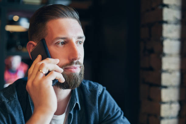 istock Confident young man talking on the mobile phone and smiling while sitting in cafe 1135358224