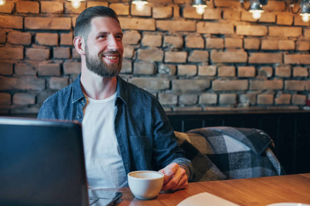 istock Young man drinking coffee in city cafe during lunch time and working on laptop 1135358263
