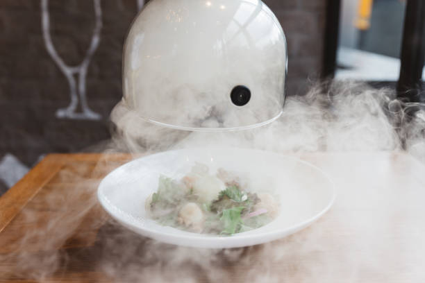 la mano maschile solleva la cloche di vetro da un piatto con cibo caldo e fumo in movimento al ristorante - ora di cibo affumicato! da vicino. - tenda igloo foto e immagini stock