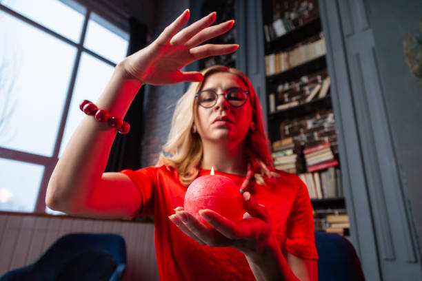 istock Blonde fortune-teller wearing red bracelet predicting future holding candle 1135366702