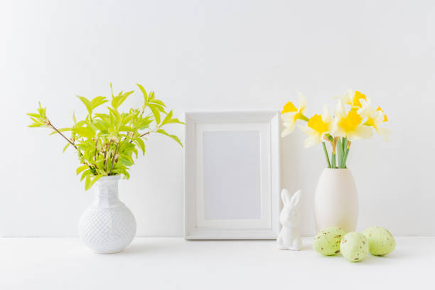 istock Home interior with easter decor. Mockup with a white frame and yellow daffodils in a vase on a light background 1135366940