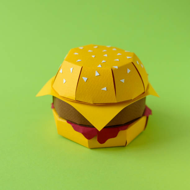 Paper cheeseburger with beef, cheese and sauce on a green background. Copy space. Creative or art food concept
