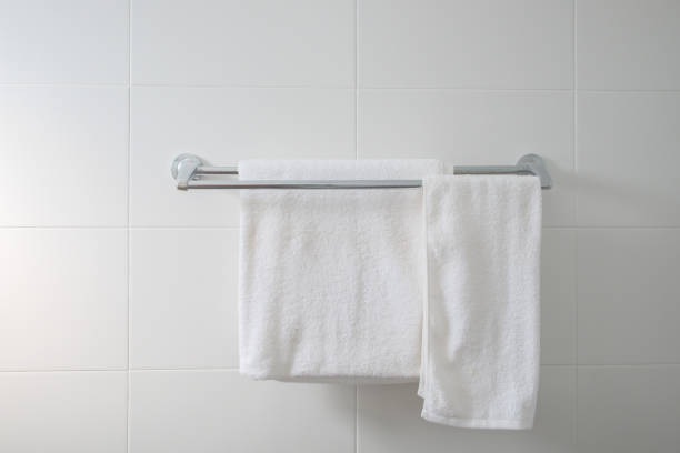Close-up empty bathroom with two white dry towel hanging on steel rail on white tile wall, interior and home decor on modern style