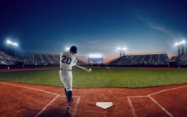 Baseball Baseball player at professional baseball stadium in evening during a game. baseball stock pictures, royalty-free photos & images
