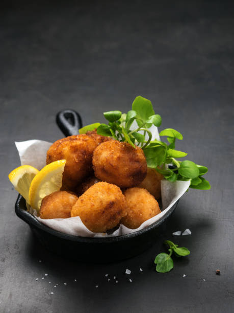 Fried Spanish bacalao croquettes in iron pan made with breaded salted codfish and served as traditional tapas or snacks. Dark background with Copy space. Fried Spanish bacalao croquettes in iron pan made with breaded salted codfish and served as traditional tapas or snacks. Dark background with Copy space. Mediterranean food. fritter photos stock pictures, royalty-free photos & images