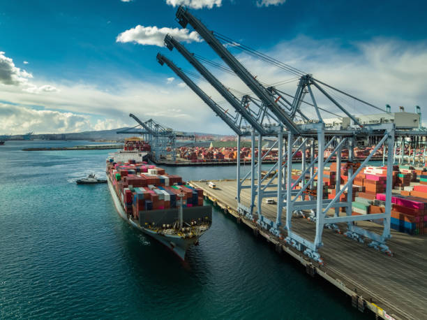 istock Cargo Ship Being Pushed Beneath Container Cranes in Port - Aerial 1135372675