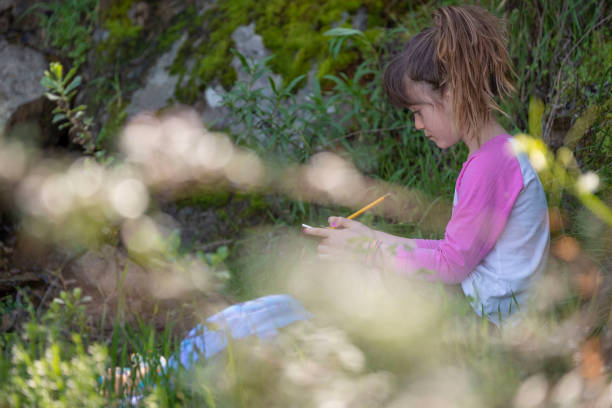 istock Young girl sketching plants on a field trip 1135373294