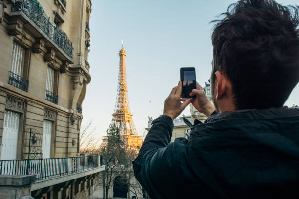 istock Young man in front of Eiffel Tower making photograph 1135374965