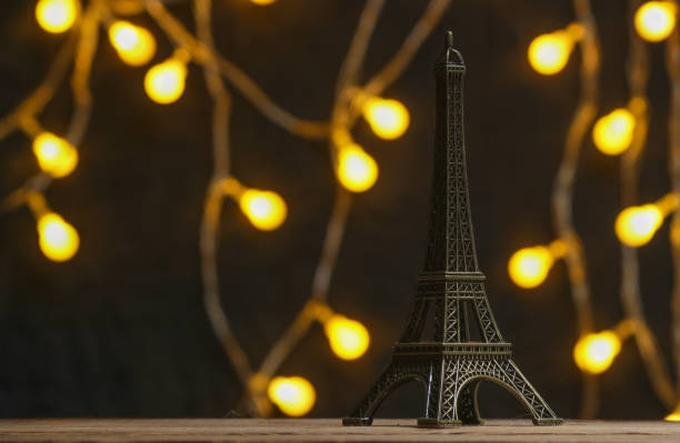 istock Bronze Statuette of eiffel tower on  dark background with garlands. 1135376876