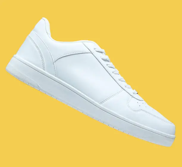 Photo of One White sneaker and isolated on yellow background