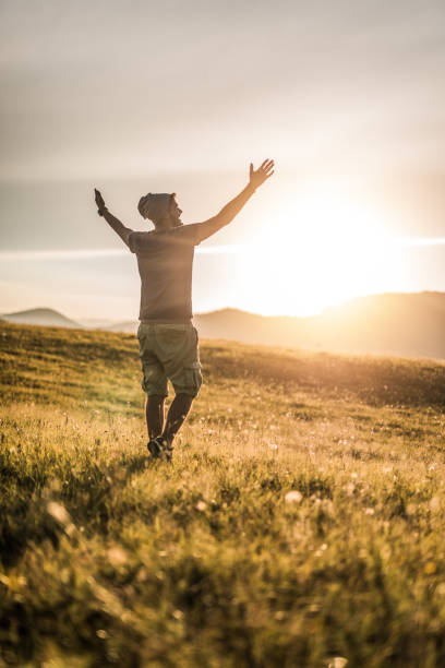 istock Happy young man enjoying a sunset on a meadow with arms up 1135384981