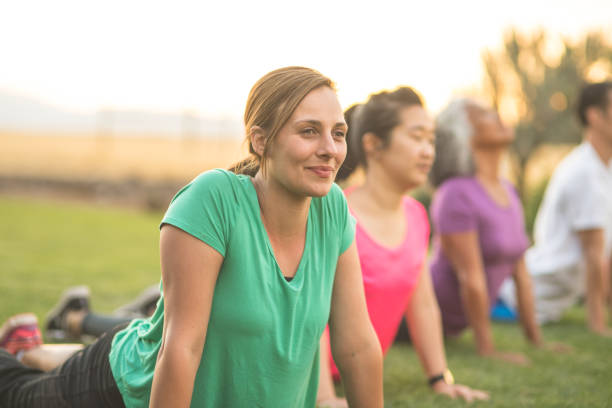 istock Group doing co-ed yoga outside in the morning 1135385112