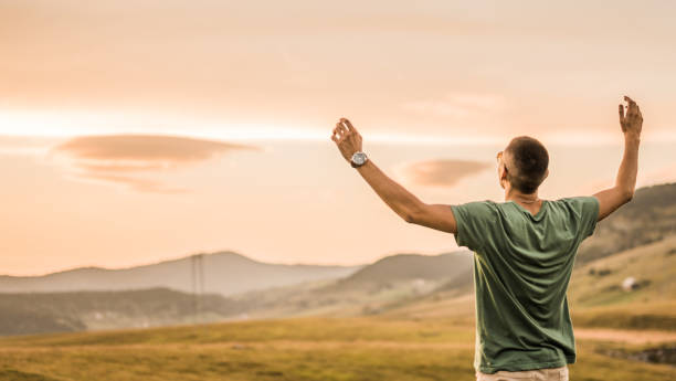 istock Young man celebrating freedom on a field during sunset. 1135385504