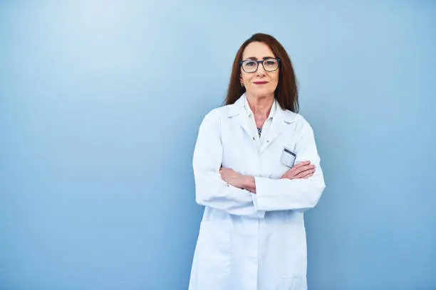 Studio portrait of a mature scientist standing against a blue background