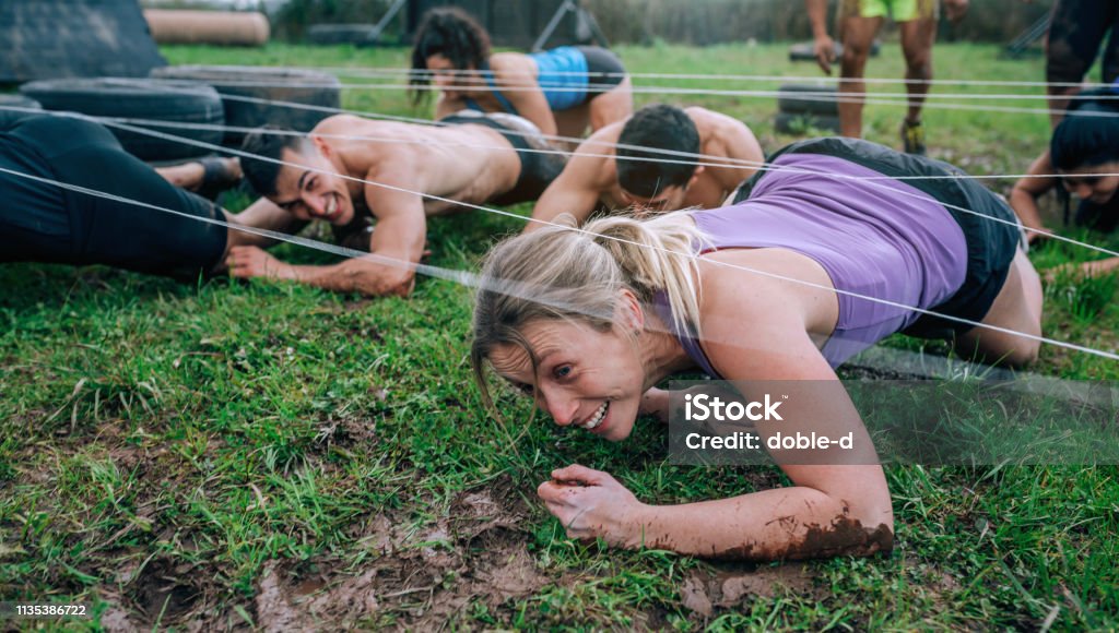 Participants in an obstacle course crawling Group of participants in an obstacle course crawling under electrified cables Obstacle Course Stock Photo