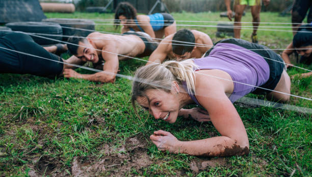 Participants in an obstacle course crawling Group of participants in an obstacle course crawling under electrified cables obstacle course stock pictures, royalty-free photos & images