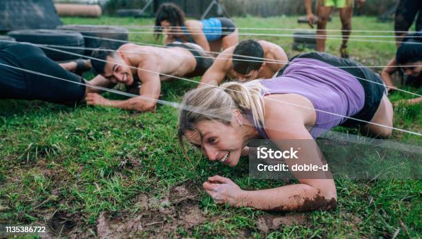 Participants In An Obstacle Course Crawling Stock Photo - Download Image Now - Obstacle Course, Running, Fitness Boot Camp
