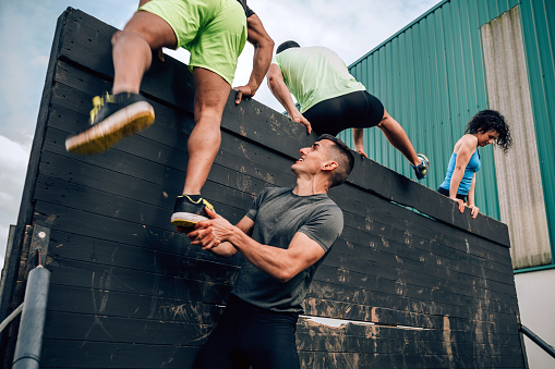 Group of participants in an obstacle course climbing a wall