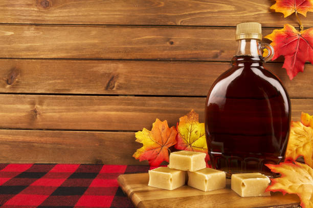 istock Maple syrup bottle on a wooden plank. Maple leaves in decoration. 1135387062