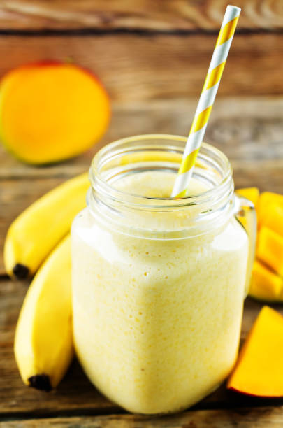 istock Mango banana smoothie on a dark wood background 1135388539