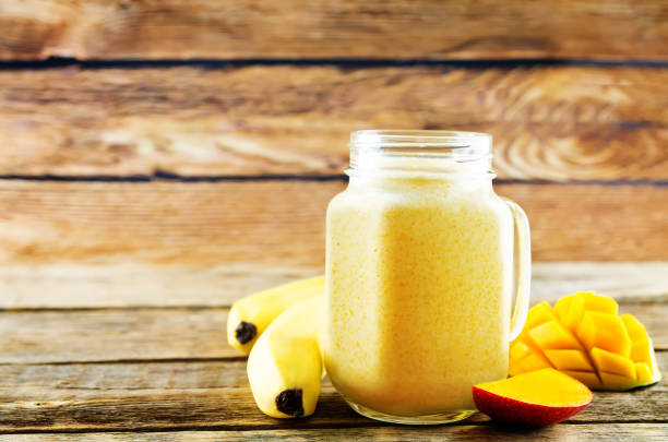 istock Mango banana smoothie on a dark wood background 1135388544