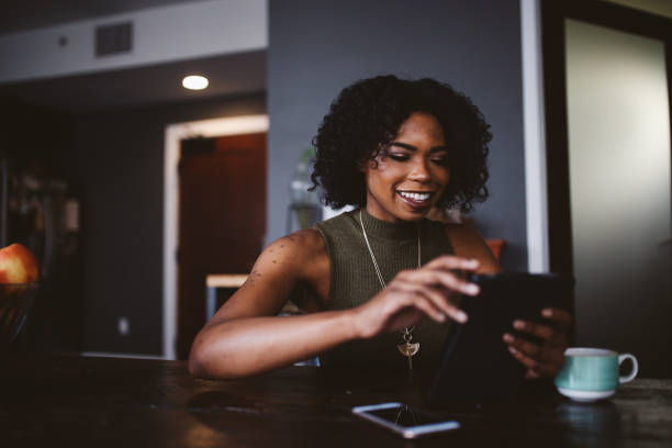 istock Young woman having a coffee in her apartment while browsing the web on tablet 1135390778