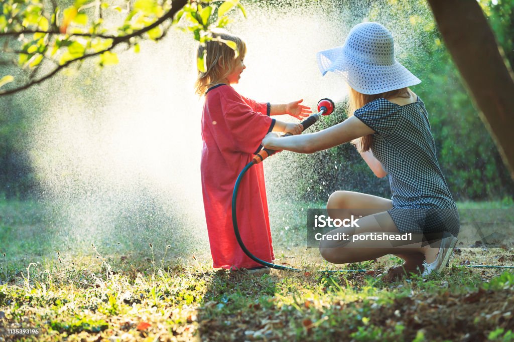 Kleiner Junge, der mit seiner Mutter im Garten wässert - Lizenzfrei Bewässern Stock-Foto