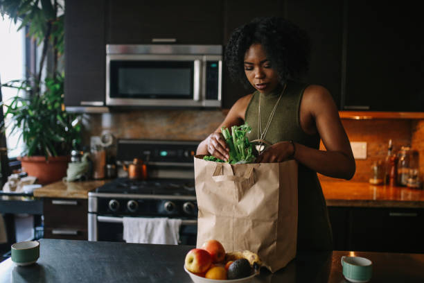 giovane donna torna a casa dalla spesa - paper bag groceries food vegetable foto e immagini stock