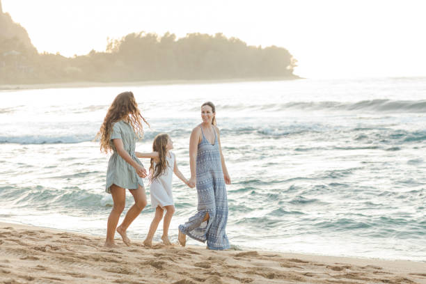 istock Mom and daughters walking together along the beach 1135393516