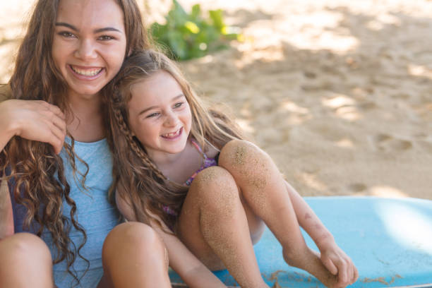 Two sisters relax with their boogie boards at the beach