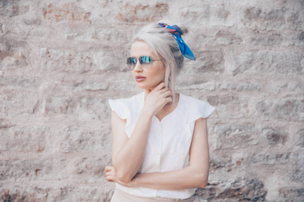 istock Young lady posing in sunglasses in front of the wall 1135393682